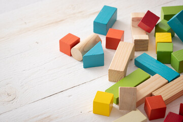 Closeup of colorful wooden toy blocks on white background wooden table. The child plays with colored cubes. - 424703037