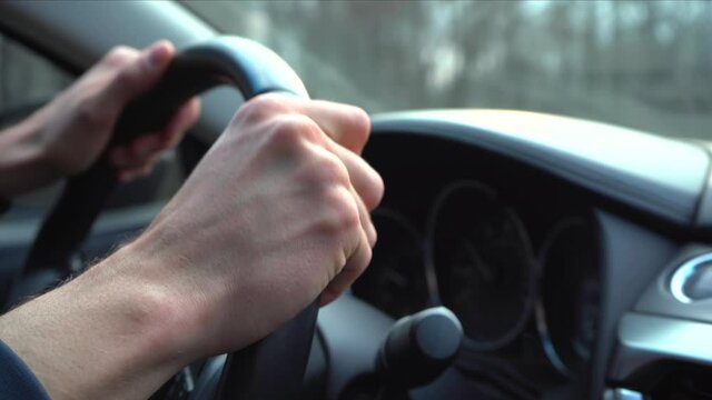 Close-Up Man Driver Hands on Car Steering Wheel. Man drives sport car in small european city at spring day. Shaky 4k footage