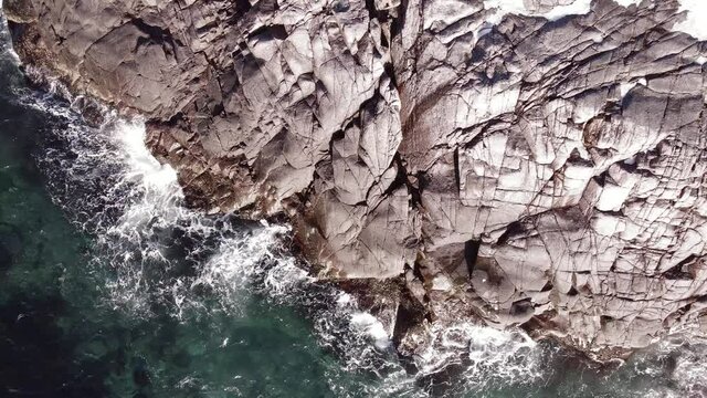 winter aerial flight top over waves rolling on artic ocean shore with round stones, ocean waves at storm