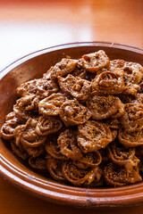 Vertical shot of fresh Chebakia sweets on a traditional moroccan big size ceramics plate on a wooden table with natural light and copy space. 