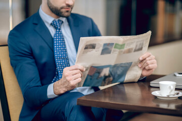 Elegant businessman in a nice suit reading a morning newspaper