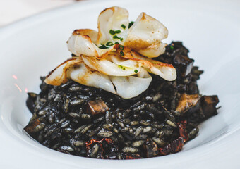 Un excelente plato gourmet de arroz negro de tinta de calamar estilo paella de marisco en un restaurante de lujo