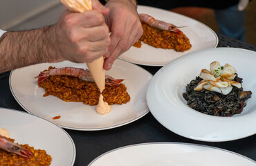Camarero sirviendo una paella de marisco gourmet con langostinos y calamares en un restaurante de...