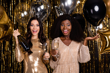 Photo of tow amazed festive ladies hold glasses champagne bottle party isolated on shine glitter...