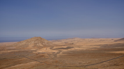Fototapeta na wymiar paisaje desertico de la isla Fuerteventura, en Canarias, Spain. A la izquierda un pequeño cerro.