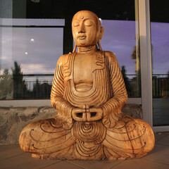 A wooden figure of a meditator in the lotus position of the Buddha.