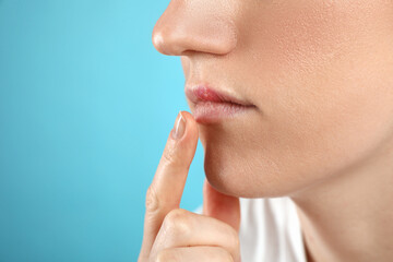 Woman suffering from herpes on light blue background, closeup. Space for text