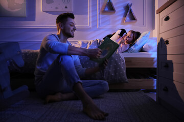 Father reading bedtime story to his daughter at home