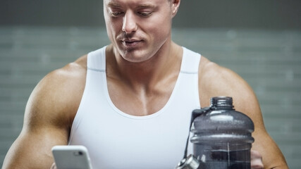Fit man at workout in gym with cell phone