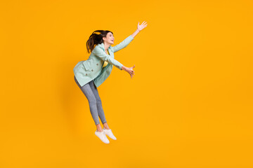 Full length photo of pretty cute young woman wear teal blazer jumping catching empty space isolated yellow color background