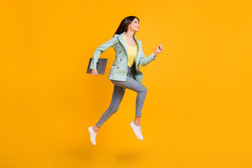 Fototapeta na wymiar Full length photo of shiny pretty lady dressed turquoise jacket jumping running holding gadget isolated yellow color background
