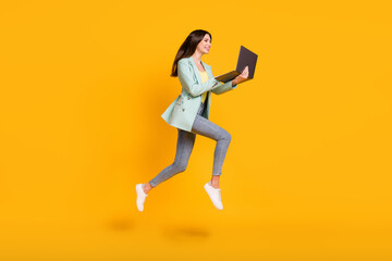Fototapeta na wymiar Full size profile side photo of young smiling positive lovely girl working in laptop jump isolated on yellow color background