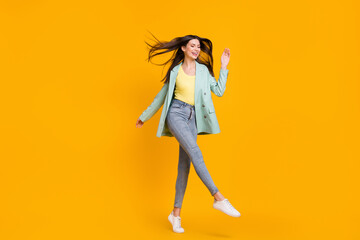 Full size photo of young cheerful smiling positive lovely girl dancing with flying hair isolated on yellow color background