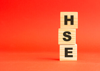 Wooden cubes with word HSE. Wooden cubes on a red background. Free space on the left.