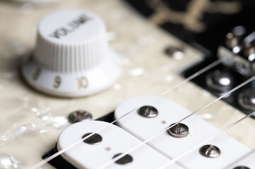 Guitar fretboard with tuning pegs and strings on a gray background. Close-up