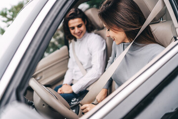 Road safety, seat belt. Young couple in the front seats fasten seat belts in the car