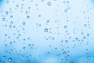 Close-up of raindrops or snow drops on a blue windowpane. Freshness background and texture of drops on the surface