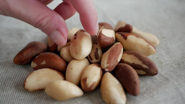Hand picks up a brazil nut from a heap, closeup