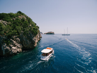 Fototapeta na wymiar A pleasure boat sails to the island of Sveti Stefan in Montenegro.