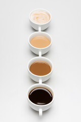 Different prepared coffee drinks with milk on white
