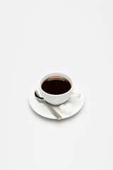 cup of prepared and fresh coffee, sugar cubes and spoon on white