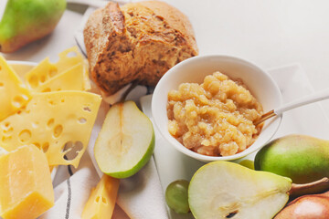 Tasty pear jam with different cheeses and bread on table