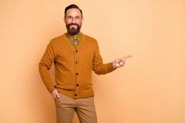 Photo of positive mature man point finger empty space for adverts promo wear sweater trousers isolated over pastel color background