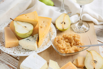 Tasty pear jam with different cheeses on table