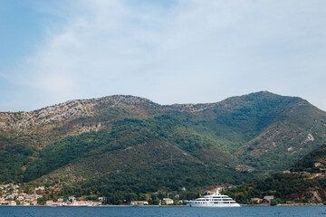 A large multi-deck white private yacht sails on the Bay of Kotor in Montenegro. The concept of the rich life of millionaires.