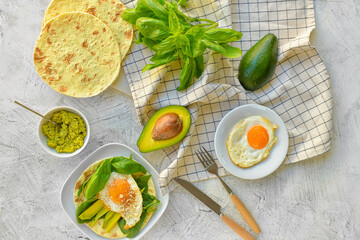 Tasty fried eggs with avocado and flatbread on grey background