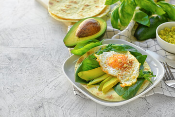 Plate with tasty fried egg, avocado and flatbread on grey background
