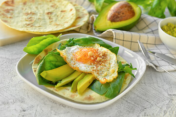 Plate with tasty fried egg, avocado and flatbread on table