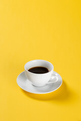 black coffee in white mug on yellow background