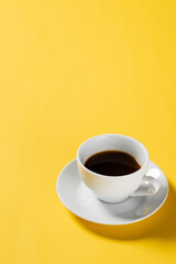 Obraz na płótnie Canvas Black coffee in white cup on yellow background