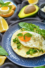 Plate with tasty fried egg with avocado and flatbread on table
