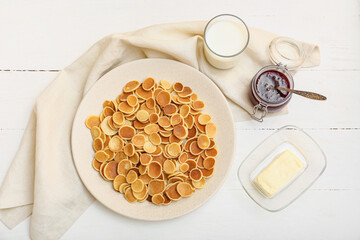 Plate with tasty mini pancakes, butter, jam and milk on table
