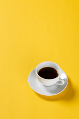high angle view of black coffee in white cup on yellow background
