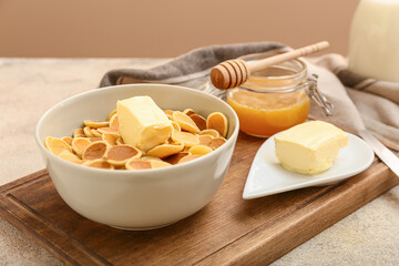 Bowl with tasty mini pancakes, butter and honey on table
