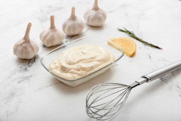 Plate with garlic sauce and ingredients on white background