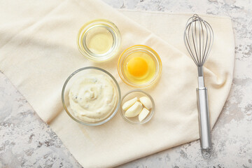 Bowl with garlic sauce and ingredients on grey background