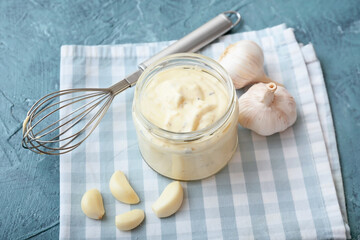 Jar with garlic sauce on color background