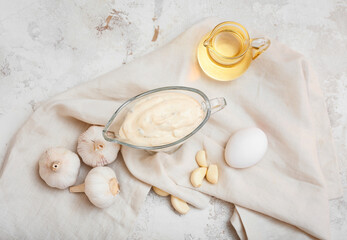 Gravy boat with garlic sauce and ingredients on grey background