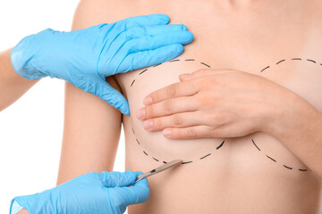 Woman and doctor with lancet on white background, closeup. Concept of breast augmentation