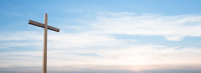 Easter concept. Cross of Jesus Christ empty over dramatic sunrise sky panorama with sclouds.