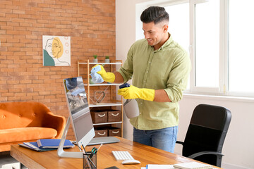 Young man cleaning computer at home