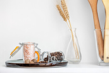 Tray with sea salt and nutmegs on table in kitchen