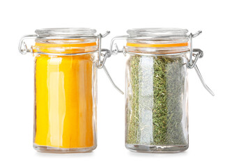 Jars with turmeric powder and dried herbs on white background