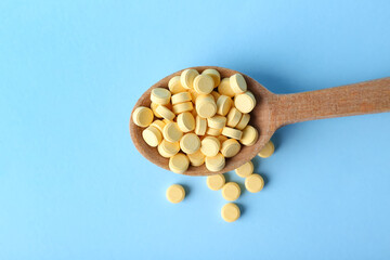 Spoon with folic acid pills on color background