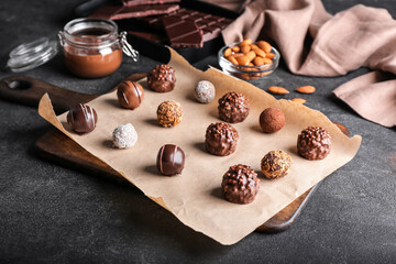 Board with sweet chocolate candies on dark background