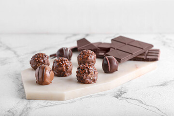 Board with sweet chocolate candies on light background